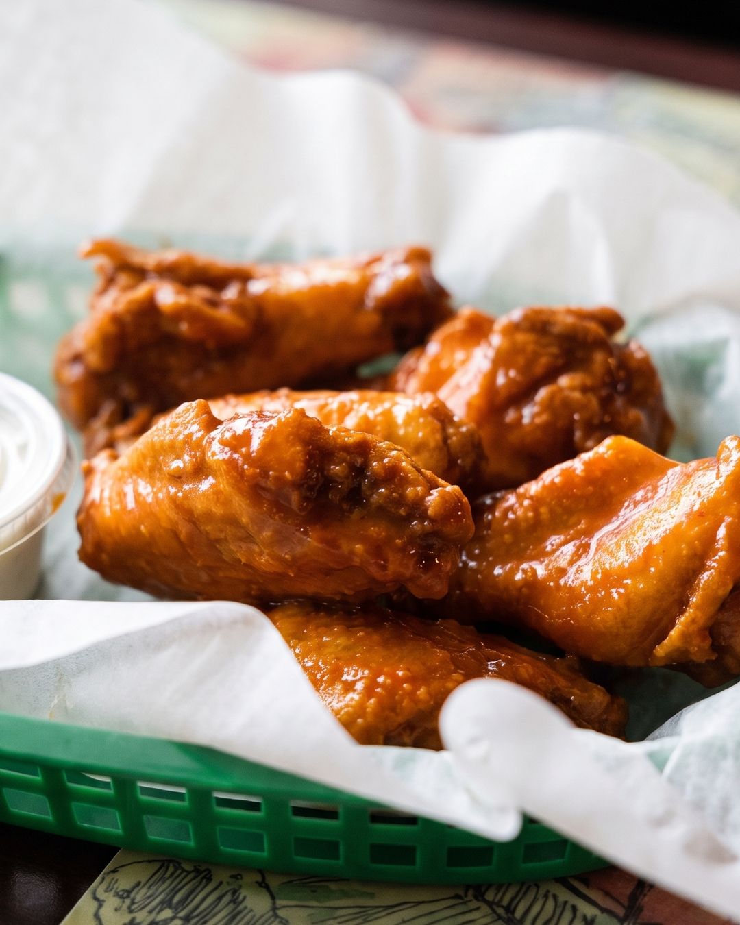 A basket of buffalo wings with dipping sauce