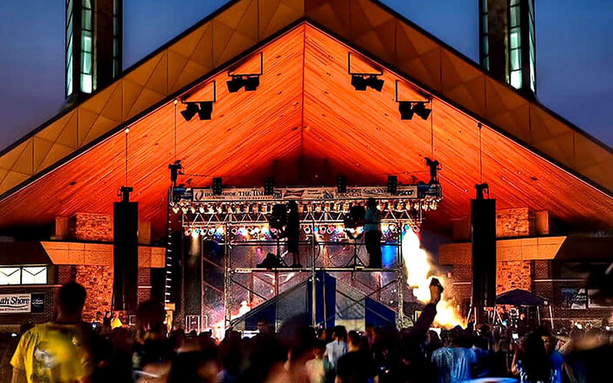 A summer evening concert at the Pavilion at Wolf Lake, stage lit under the timber roof