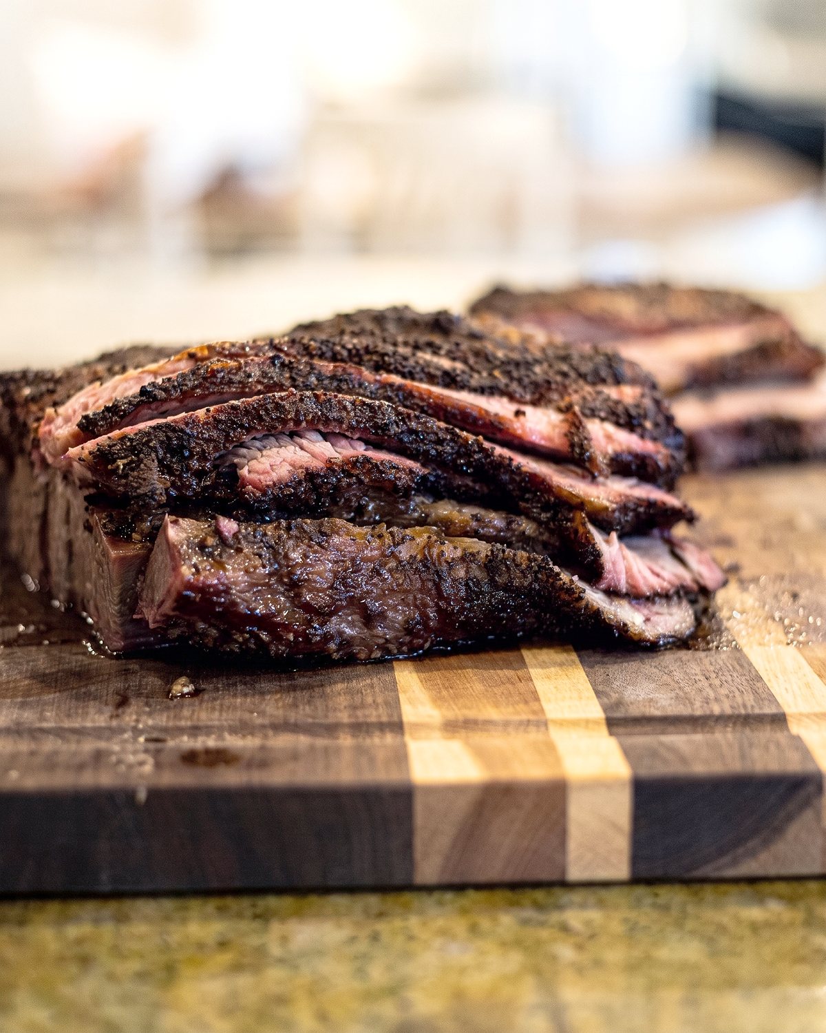 Sliced smoked beef brisket with a dark bark on a butcher block