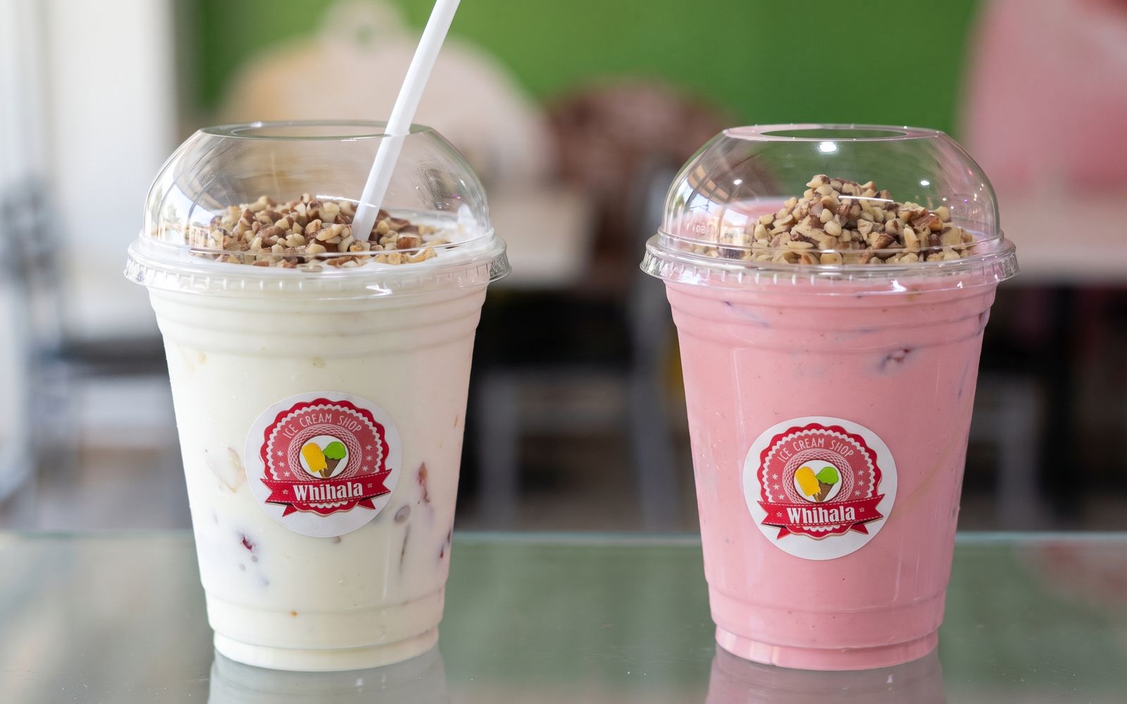 Two Whihala shakes in branded cups, topped with chopped nuts