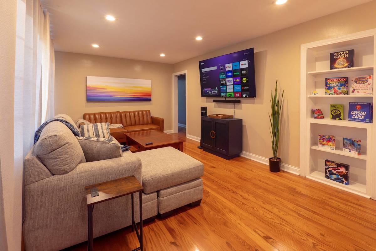 Living room with sectional, 70-inch Roku TV and a shelf of board games