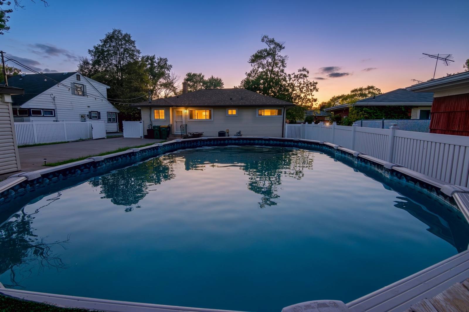 Backyard pool at twilight at MiniGolfHouse Munster, house windows glowing