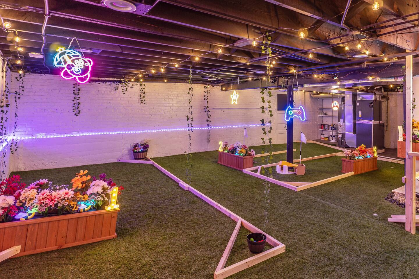 The six-hole basement mini golf course at night, neon signs glowing